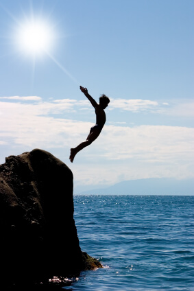 Boy jumping off a cliff